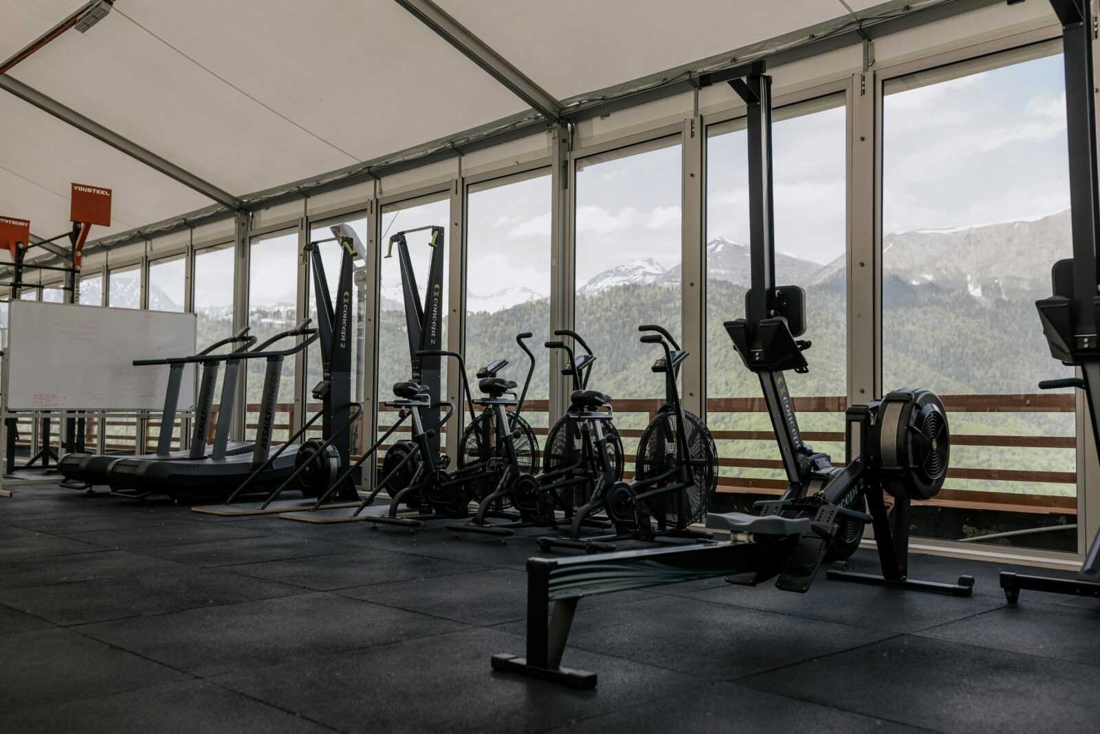 Spacious indoor gym featuring state-of-the-art equipment with scenic mountain views outside large windows.